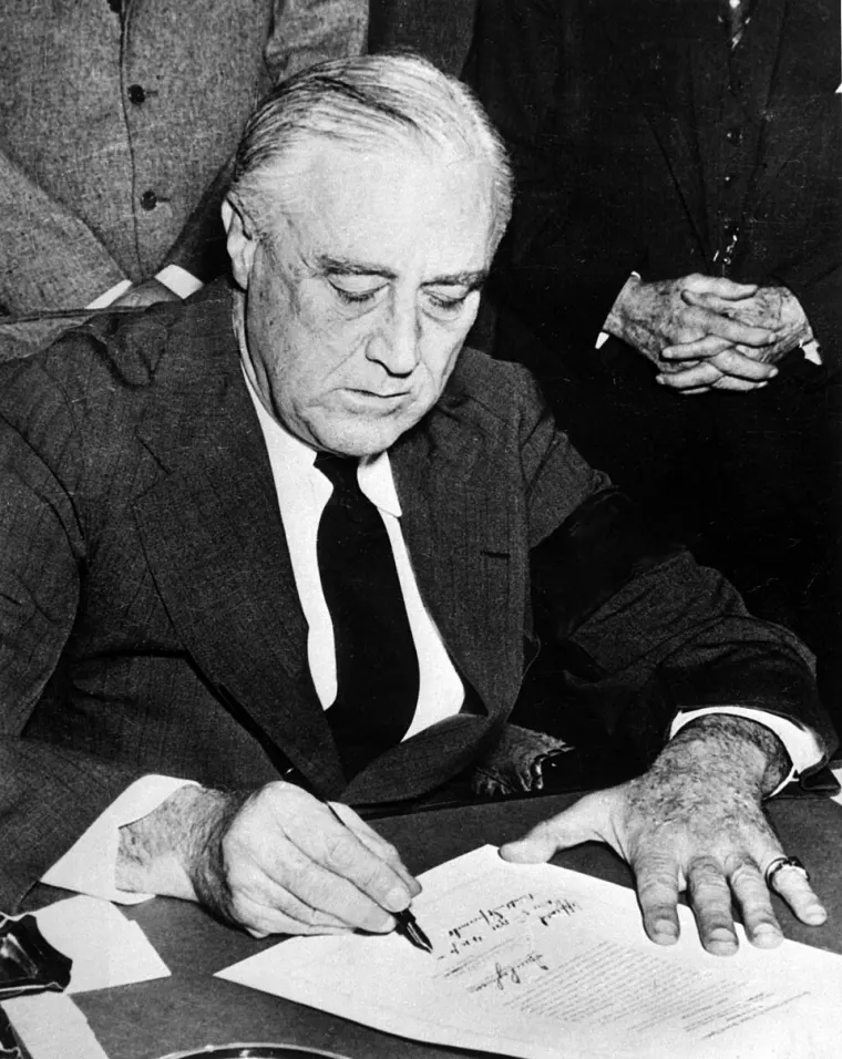 Franklin D. Roosevelt signing a document.